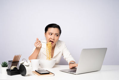 Mid adult man using laptop on table against white background