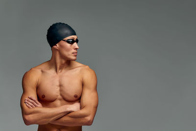 Close-up of shirtless man standing against gray background