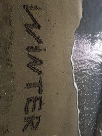 High angle view of text on wet sand