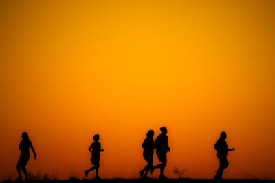 Silhouette people against orange sky