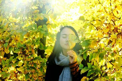 Portrait of young woman standing against plants