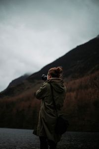 Rear view of woman standing on mountain against sky