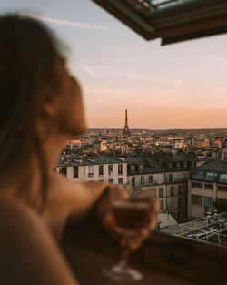 Close-up of woman holding wineglass looking at city