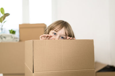 Portrait of cute boy peeking through box