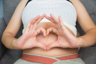 Midsection of woman with heart shape sitting on floor