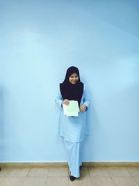 Portrait of woman standing against wall