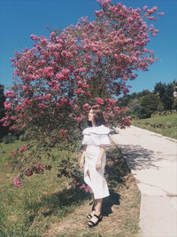 Young woman standing by flowering tree