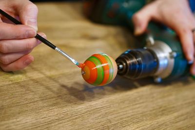 Cropped image of hand painting easter egg on table