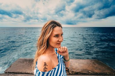 Portrait of woman standing against sea against sky