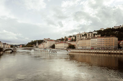 Buildings by river against sky