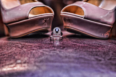 Close-up of wedding rings with sandals on table