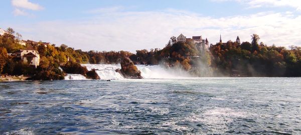 Scenic view of waterfall by sea against sky