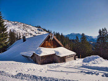 Snow covered landscape and houses against clear sky