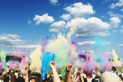 People throwing colored powder in air during holi festival against sky