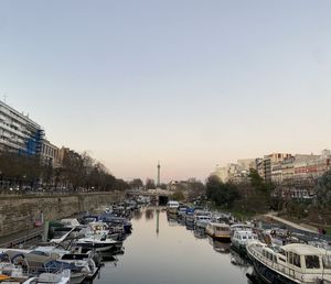 Boats moored at harbor in city against clear sky