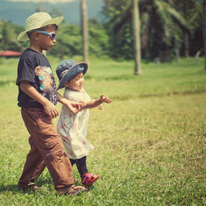 Siblings walking on lawn