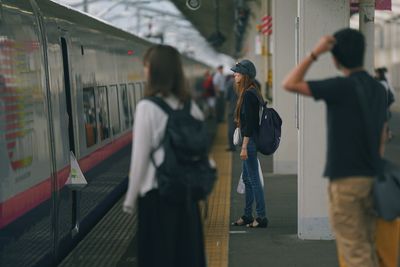 Rear view of people walking on railroad station platform