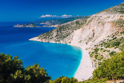 High angle view of sea and trees against blue sky