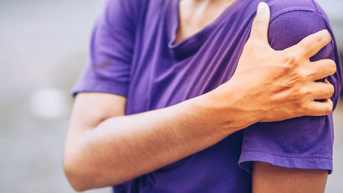 Midsection of woman standing against purple wall