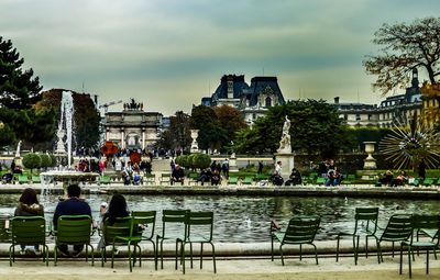 People by swimming pool in city against sky