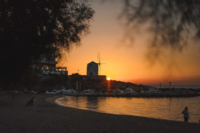 Silhouette of building by sea against sky during sunset