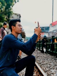 Young man looking away while sitting on mobile phone