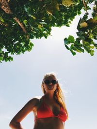 Portrait of woman in bikini at beach against sky