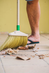 Low section of man cleaning floor with broom