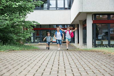 Happy children run on the background of the school or from school. the beginning of the school year