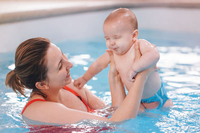 Woman holding baby boy in swimming pool