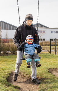 Grandfather swinging baby girl at park