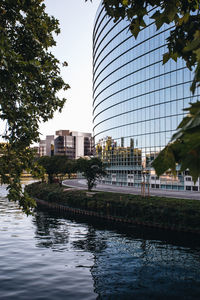 Buildings by river in city against sky