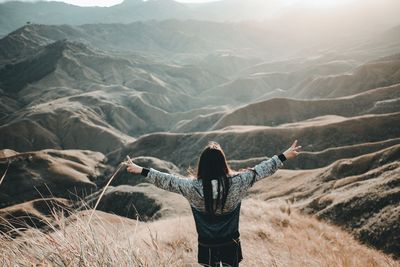 Rear view of woman gesturing peace sign on mountain