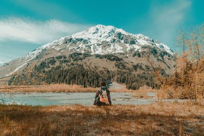 Woman standing on snowcapped mountain against sky