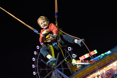 Low angle view of boy bungee jumping at night