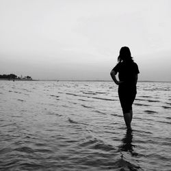 Scenic view of woman standing in sea against sky