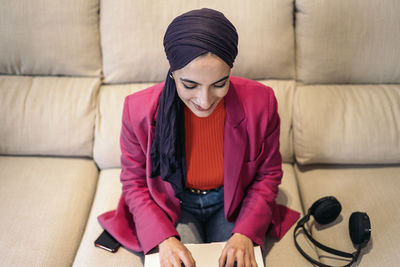 Portrait of young woman sitting on sofa at home