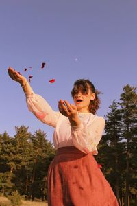 Portrait of girl holding plant against sky