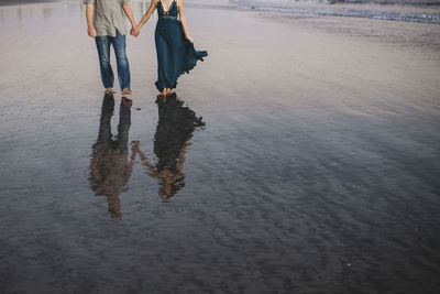 Low section of woman standing on wet beach