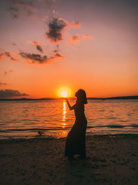 Woman standing at beach during sunset