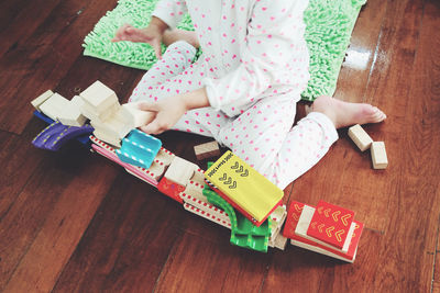 Low section of girl playing with toys on hardwood floor at home