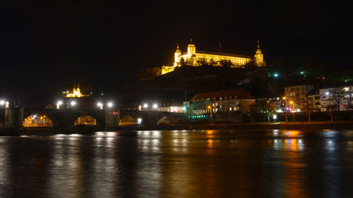 Illuminated bridge over river at night