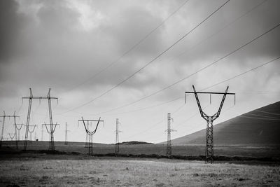 Electricity pylon on field against sky