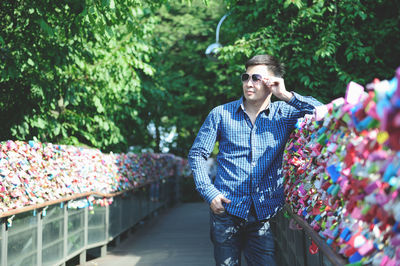 Man wearing sunglasses standing by love locks on railing