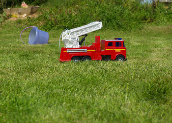 Fire rescue toy car in green grass field.
red tractor on field.