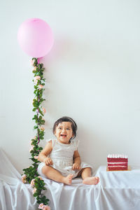 Portrait of smiling girl with balloons against wall