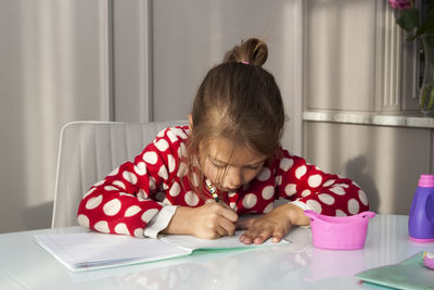 Portrait of girl sitting on table at home