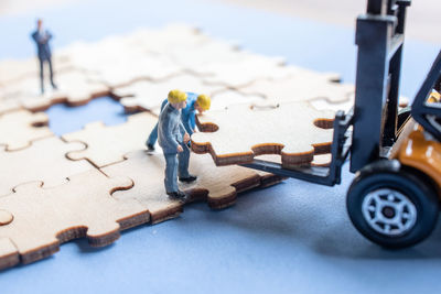 Close-up of toy earth mover and figurines picking jigsaw piece