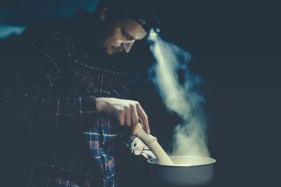 Side view of man preparing food at night
