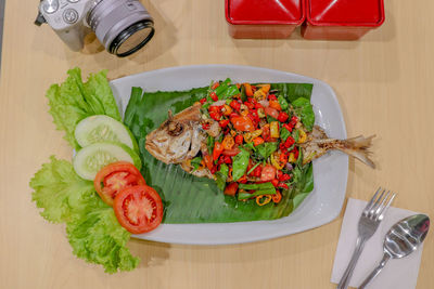 High angle view of fried fish with red and orange chilli vegetables in plate on table